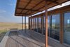 Modern home with Outdoor, Desert, Shrubs, Small Patio, Porch, Deck, Wood Patio, Porch, Deck, Decking Patio, Porch, Deck, and Side Yard. Large canopies shade the retreat’s southern elevations, rendering the interior and ipe wood patio comfortable in the Texas heat. Photo of Petite Prefab with Stunning Views of the Texas Landscape