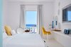 Modern home with Bedroom, Chair, Bed, and Shelves. In the Seabreeze Room, marble floors and floating shelves repeat the use of this local material. Custom Flos lighting design allows the space to softly glow, while a private balcony looks out to the rest of the coastal property. Photo 8 of Myconian Ambassador Hotel