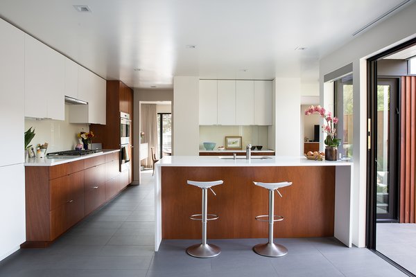 To match the original mahogany paneling, a set of new cabinets, crafted by by Benchmarc Woodworking, are installed in the kitchen. Dark bronze anodized doors from Fleetwood open up the space to the courtyard.