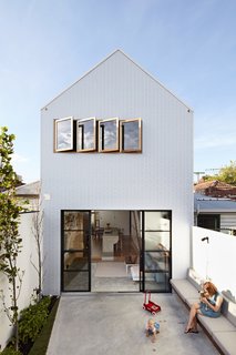 The Scyon Axon cladding of this gabled Melbourne addition gleams at midday. Designer Dan Gayfer punctuated the facade with sliding glass doors and a row of windows to fill the narrow home with sunlight.