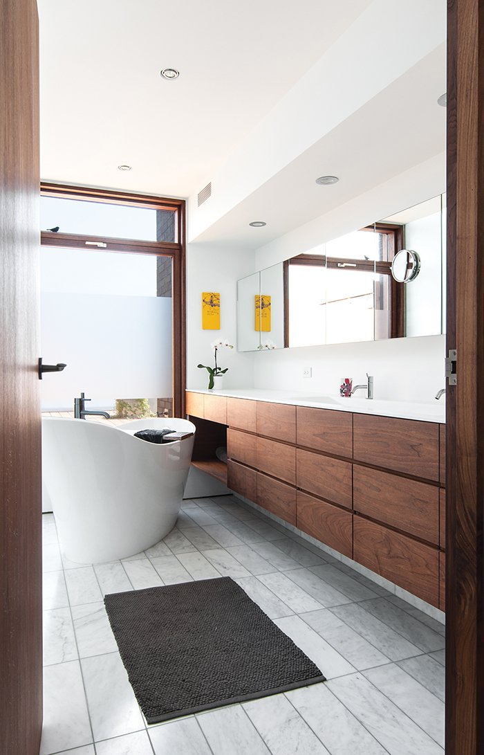 The bathtub faces a Spanish-cedar-framed window overlooking the back deck. Once the outside plants have grown up enough to provide privacy, the adhesive film on the window will be removed.