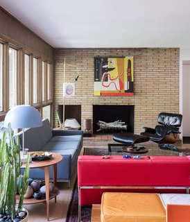 In the living room, a vintage Paul McCobb sofa, a Gio Ponti side table, and an Eames lounge echo the home’s midcentury architecture—as does the thrifted red Florence Knoll Parallel Bar sofa that lends the room a shot of color.