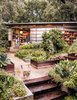 Modern home with Outdoor, Back Yard, Trees, Raised Planters, Gardens, Walkways, Shrubs, Flowers, Garden, and Planters Patio, Porch, Deck. A section of the facade—a cross between a shoji screen and a barn door—slides open. Planter boxes contain edible varieties that fuel Mary’s culinary explorations. Photo 10 of Modernist Gem Revival