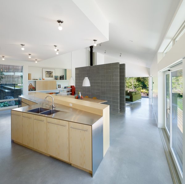 The kitchen includes custom ash cabinets made by JMV Woodworks paired with stainless-steel countertops.