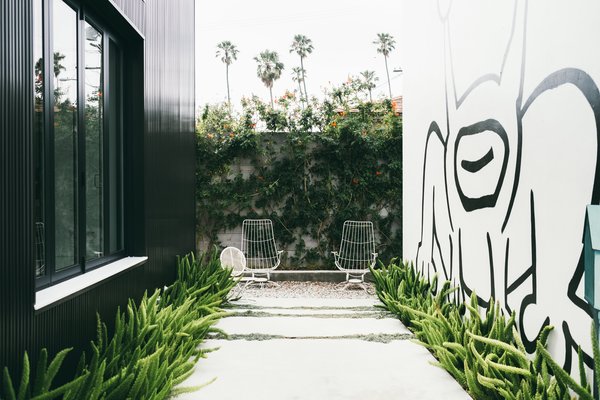 A giant mural by the artist Daniel Johnston dominates the outdoor garden of an art-filled home in Venice designed by Chris Rudin.