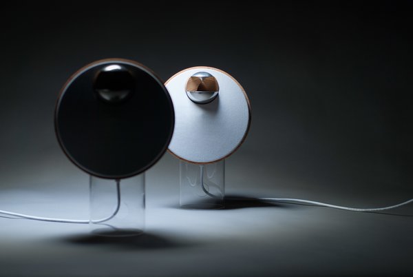 BeoLab S, designed by Tuomas Hämäläinen, aimed to combine the simplicity of one-point music systems with the wide sound stage of traditional stereo speaker systems. The warm, wooden loudspeakers perch atop translucent cylindrical stands.