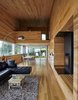 Modern home with Living Room, Sofa, Floor Lighting, Rug Floor, Standard Layout Fireplace, and Medium Hardwood Floor. The interior of locally milled poplar contrasts with the home’s metal exterior. Thanks to the six-degree pitch of the site, the dining area leads directly to the yard, while the living room ends with a balcony that’s high above the ground. Photo 2 of Sliding House