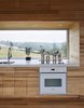 Modern home with Kitchen, Drop In Sink, Wood Counter, Wood Cabinet, Cooktops, and Wall Oven. The focal point of the home is the long Alumicor window that reveals the slope of the site. Photo 4 of Sliding House