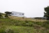 Modern home with Side Yard, Exterior, Slope, Field, Metal Siding Material, and House Building Type. Imagined as a jewel box on a hill, Sliding House takes the place of a barn that once stood on this Nova Scotia site. Its form follows the slope of the land, while the windows are parallel with the horizon, setting up a tension between a plumb interior and a slanted exterior. The tilt of the structure isn’t just a visual trick—it also helps the roof to drain. When the distinctive windows are lit from within, the house serves as a beacon for local sailors. Photo of Sliding House