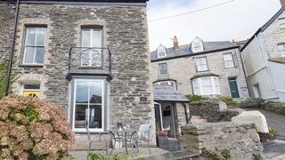 Designed by Cornish interior designer and home renovation expert Nicola O'Mara, Albany in Port Isaac is a peaceful haven decked in sea-gray wood panels, exposed slate walls, and midcentury furniture. 