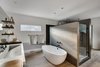 Modern home with Bath Room, Medium Hardwood Floor, Drop In Sink, Freestanding Tub, Enclosed Shower, and Stone Tile Wall. Glenrock tiles in light grey provide dramatic contrast against the freestanding tub by Victoria + Albert. Juilland used the same tiles, though in a darker shade, on the inside of the shower. Photo 7 of Frischkorn Ranch