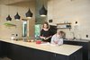 Modern home with Kitchen, Wood Counter, Drop In Sink, Wood Backsplashe, Ceiling Lighting, Pendant Lighting, Wall Lighting, Refrigerator, and Range. In the kitchen both the walls and the countertop are made of birch plywood. A quartet of black Tom Dixon Beat lights hangs overhead. Photo 3 of The Land House