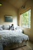 Modern home with Bedroom, Bed, Bench, Wall Lighting, and Light Hardwood Floor. Emerson, 8, reads in a sitting room where overnight guests stay. Photo 7 of The Land House