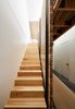 Modern home with Wood Tread and Exterior. By eliminating the attic and carving out a former crawl space, Red Dot Studio created room for the residents’ bedrooms underneath the primary living areas. The slatted-hickory-and-glass bridge allows light from a row of skylights to penetrate deep into the lower level. Photo 5 of Dogpatch Cottage