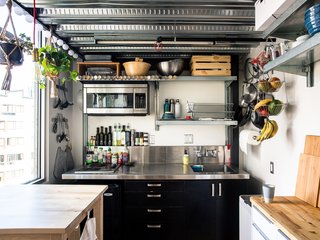 The kitchen, located behind the stairs and underneath Max’s  bedroom, is all electric, with two  burners, a rice cooker, a slow cooker, and a toaster oven. Max added industrial shelving and  a butcher block. “Vertical storage,” he notes, “is very important.”