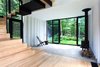 Modern home with Windows and Sliding Window Type. The addition rises above the original shack’s 400- square-foot concrete foundation, which is partially visible in the living room. A Cricket patio chair by Hershy Way is used for indoor seating opposite a Morsø wood-burning stove. Photo 5 of La Colombière