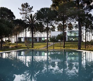 Sitting across from a deserted beach on a private plot surrounded by a pine forest is a large modernist vacation home that's ideal for families and large groups—and is just an hour drive away from Lisbon. 
Comprised of three conjoined rectilinear structures with generous glazing and full-height windows, Villa Caetana allows guests to comfortably enjoy everything about its tranquil natural surroundings, both indoors and out.