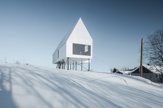 White concrete panel cladding and corrugated steel roof panels give this cabin a crisp, geometric form that almost melts into the landscape on bleary, snowy days.