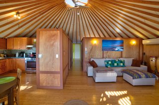 The exposed beams of the yurt lead up to a central skylight that helps the space feel bright and airy.