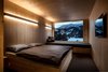 Modern home with Bedroom, Bench, Bed, Wall Lighting, and Carpet Floor. The ceilings, floors, and walls of the rooms are constructed from natural, unfinished plywood. Photo 6 of Revier Mountain Lodge