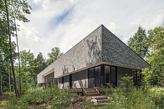 Vince and Adrienne Murphy’s rural retreat is clad in gray shingles and gray-stained pine. “They wanted the cottage to meld into the woods and be visually quiet,” says architect Kelly Doran, who worked with Portico Timber Frames to build the 2,500-square-foot home.