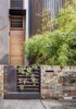 Modern home with Exterior, Concrete Siding Material, Wood Siding Material, House, and Stone Siding Material. The gate leading to Geoff Carroll and Julie Young’s rebuilt terrace house in an inner suburb of Sydney, Australia, holds an array of succulents, signaling what lies within: a greenery-filled home that includes a central courtyard, vertical gardens, aquaponics and rain filter systems, and even a chicken coop. Architect Clinton Cole of CplusC Architectural Workshop led a team of collaborators in revamping the property. Photo 2 of Aquas Perma Solar Firma