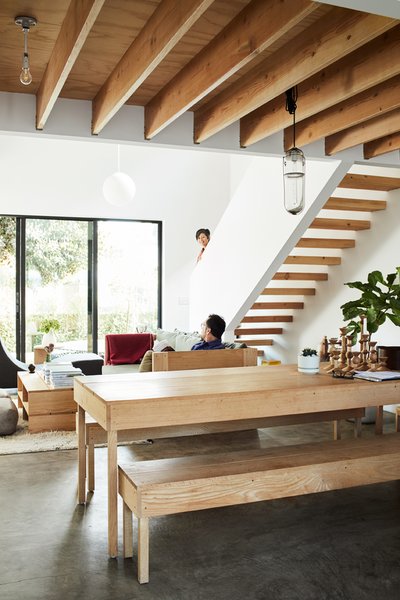 A Peter Ivy pendant hangs over the dining table and benches, also by Taku. At one end is a collection of candlesticks, prototypes for Tortoise that will be manufactured in Hokkaido.  The simple wood treads on the open-riser staircase complement the unfinished ceiling beams.