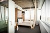 Modern home with Bedroom, Carpet Floor, Bed, and Pendant Lighting. There are no closets and no minibars in the guest rooms, reflecting the designers' minimalist approach. Features include a curved wooden headboard and a hammock hanging from the ceiling. Unfinished ceilings reveal partitions of the old structure, even down to the screws. Photo 8 of Hotel Daniel