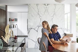 Resident Simon Mason, joined by his daughter, sits on a leather-upholstered Bertoia side chair.