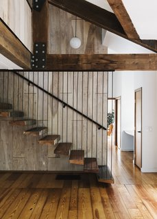 Floating against birch paneling, the main stair incorporates treads salvaged from old barn wood.