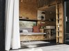 Modern home with Living Room, Coffee Tables, and Sofa. In addition to having a queen bed upstairs, Ryan built a sofa that converts to a twin, based on a design by architect Sean O’Neill. The transformable unit cost $500 in upholstery, $35 in wood, and $4 in hinges. Photo 5 of Elsewhere Cabin Retreat