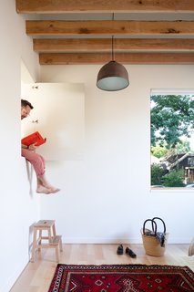 The master bedroom has access to the netted play nook through a whimsical door that punches through the upper part of a wall. A repurposed street lamp from Copenhagen is suspended from the ceiling. 