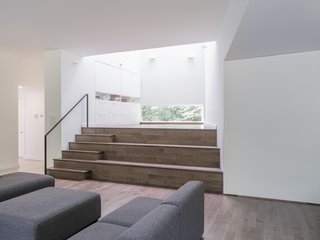 At the bottom of the 34-foot-tall light well sits an airy, open stage, which is a beloved spot for the family of musicians. "While the stage easily acts as a place for performance—from hosting a jam session to children’s impromptu concerts, it can also double as a seating area for the living room," notes co-founder of Acre Architects Stephen Kopp. "We were part of a lecture that the client gave from the living room, and it really felt like an intimate fireside chat."