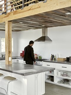 This kitchen is outfitted with concrete counters and floors and off-grid-friendly low-energy appliances. The ceiling is paneled in reclaimed barn wood.