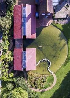 A winding path connects the front parking area to the rear of the structures before leading to stepping stones that playfully connect with the guesthouse.