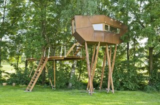 Nestled in a small Austrian community between Salzburg and Linz, this charming tree house rests primarily on eight asymmetrical and inclined oak support beams. With an oxidized Cor-Ten steel facade, the perched cabin yields a unique sculptural effect due to its sloping surfaces. Inside, a large picture window frames beautiful views of the trees and meadow beyond.