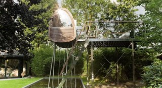 Surrounded by tall bamboo, the Frog Prince tree house floats above a shallow pond in a private garden in Münster, Germany.