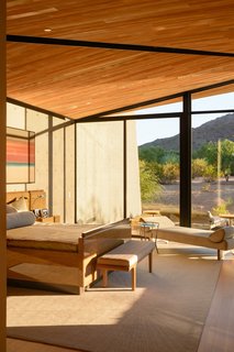 A bedroom features floor-to-ceiling windows, allowing the space to capture plenty of sunlight.