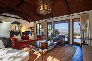 The main living area sits underneath dark wood beams and includes a wall of windows to take in the hillside views.