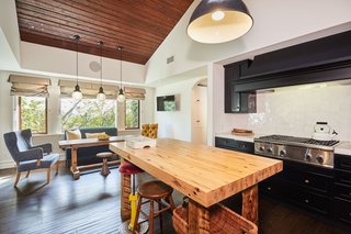 The kitchen features a large butcher-block island, as well as a vaulted, wood-paneled ceiling.