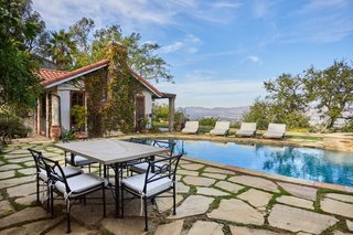 A stone patio surrounds the pool and spa, providing plenty of space for relaxing.