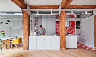 White built-in cabinetry delightfully contrasts with the home's original wood beams and pillars, which the architects have left exposed (along with the aluminum ductwork and perforated metal) to pay homage to the building's industrial past.