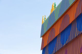 By overlapping rows of six-foot-long wooden battens—painted with a geometric pattern on the outside face, along with a different color on each side—the designers cleverly translated the inspiring effect of walking through the aisles of African fabric markets into architectural terms.