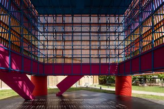 Inside, the "backstage" area of the cube reveals a bright blue, wooden space-frame. Guests are invited to climb up the pink pair of processional staircases, where they can then wind through the structure, gazing upon the mesmerizing intersection of battens and wires.