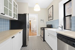 Recently remodeled, the light-filled kitchen features stainless-steel appliances, black-and-white tiled flooring, as well as plenty of storage.