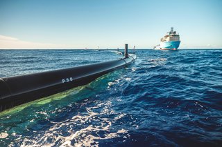 A boat helps position the plastic-trapping system in the open ocean.