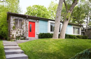 Sitting alongside five other Lustron homes on Nicollet Avenue in Minneapolis, this rare prefab is cladded in sleek, "surf-blue" steel panels. A bright red door welcomes guests inside.