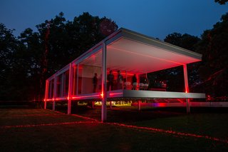 The Farnsworth House illuminated by latticed red lasers that extend out into the home's natural surroundings.