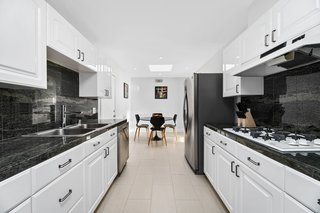 The galley kitchen features crisp white cabinetry with contrasting black accents.