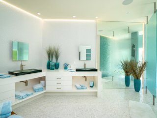 The master bathroom is brightened by custom lighting and natural light shining through the tempered glass shower wall.